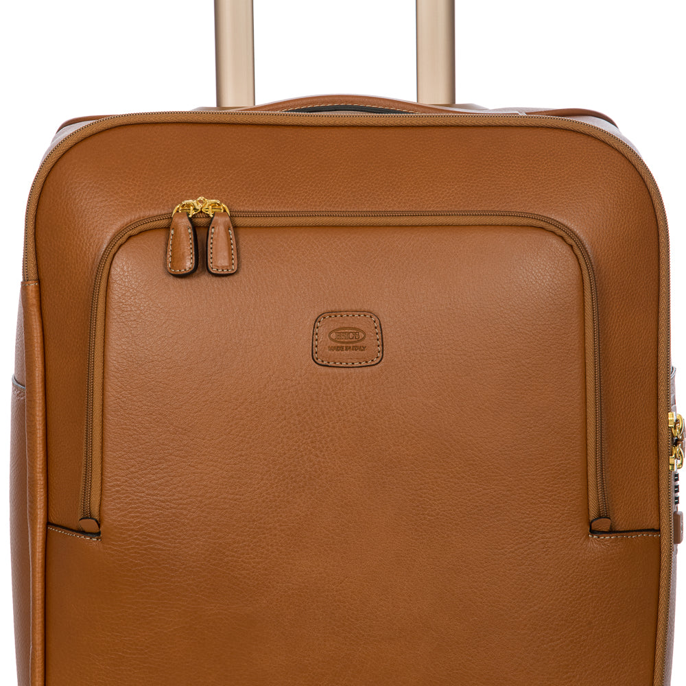 Bric's Cabin Spinner Suitcase Pelle in tan with four wheels, telescopic handle, and durable hard shell for travel.