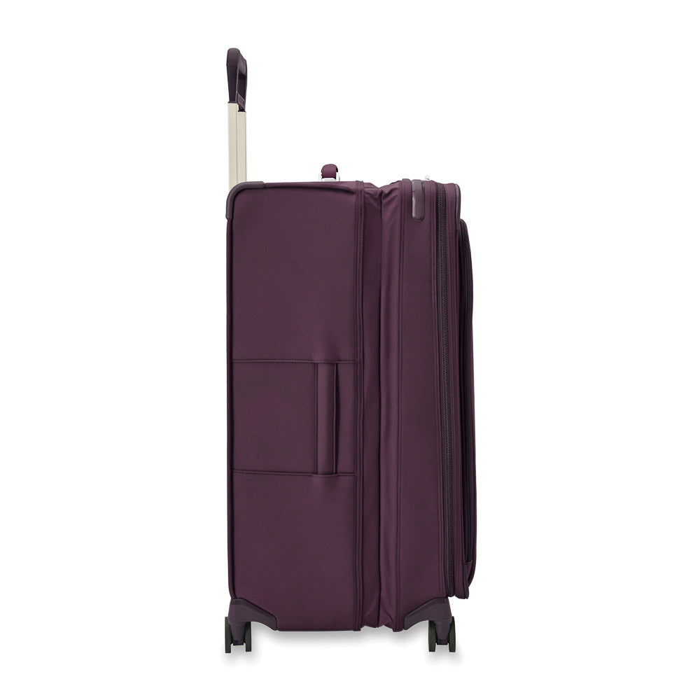 Extra large expandable spinner suitcase in plum by Briggs & Riley, featuring four wheels and a sturdy handle for easy travel.