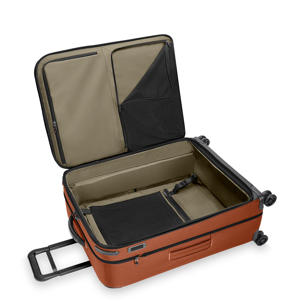 Large expandable spinner suitcase in canyon color by Briggs & Riley, showcasing smooth wheels and durable exterior.