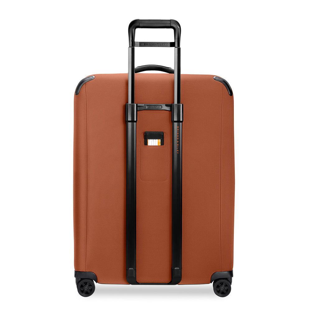 Large expandable spinner suitcase by Briggs & Riley in canyon color, featuring four wheels and sturdy handle for easy travel.