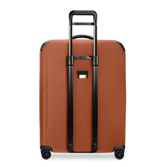 Large expandable spinner suitcase by Briggs & Riley in canyon color, featuring four wheels and sturdy handle for easy travel.